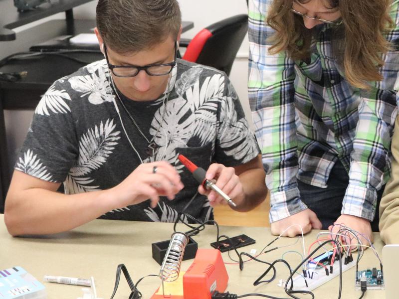 Students working on a research project with a soldering iron.